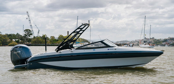 A Yamaha outboard motor speedboat with a black wakeboard tower, shown on the water under a cloudy sky.