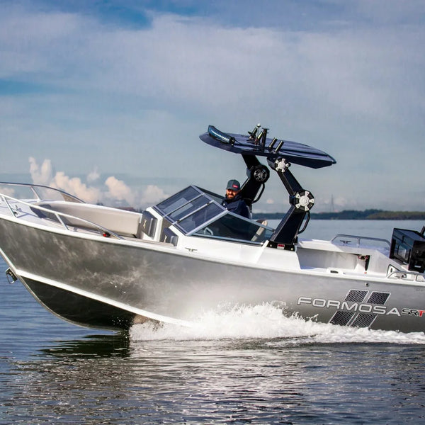 A Formosa Yacht motorboat with a wakeboard tower and black outboard motor, shown in motion on water with a driver visible inside.