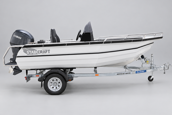 A white Stabcraft boat on a metal trailer parked in front of a Yamaha dealership building.