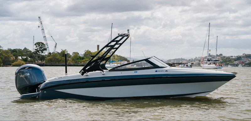 A Yamaha outboard motor speedboat with a black wakeboard tower, shown on the water under a cloudy sky.