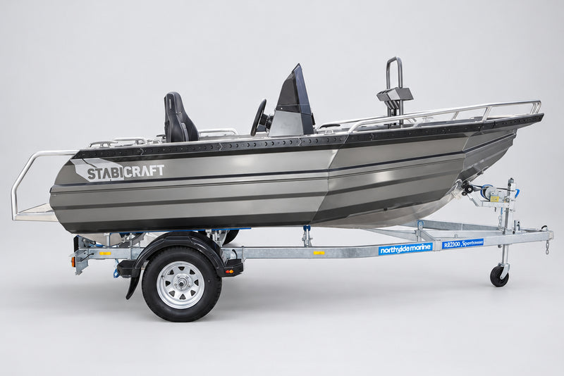 A gray and black Stabicraft motorboat on a dual-axle trailer, parked outdoors in front of a Yamaha dealership building.