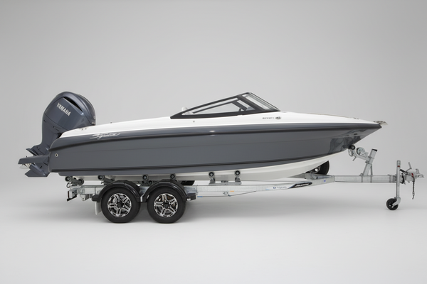A Haines Signature 620BRX Bowrider with Yamaha outboard motor speedboat on a dual-axle trailer, parked in front of a boat dealership building with a Yamaha logo.