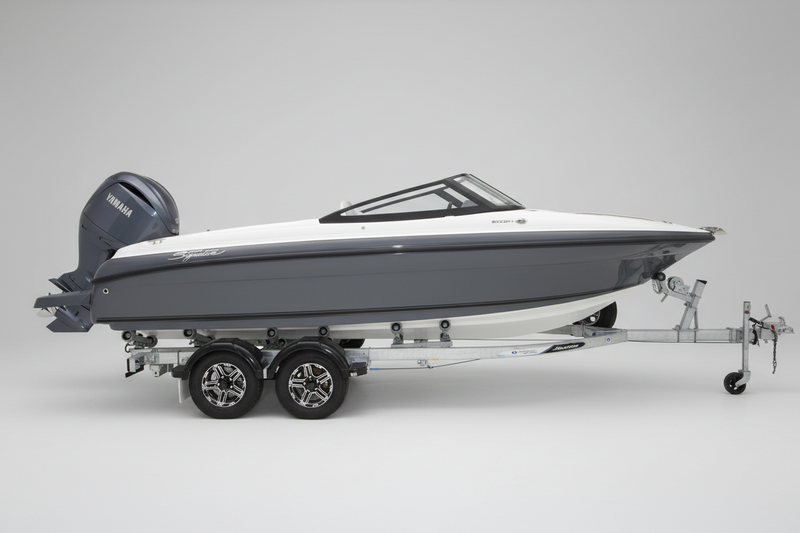 A Haines Signature 620BRX Bowrider with Yamaha outboard motor speedboat on a dual-axle trailer, parked in front of a boat dealership building with a Yamaha logo.
